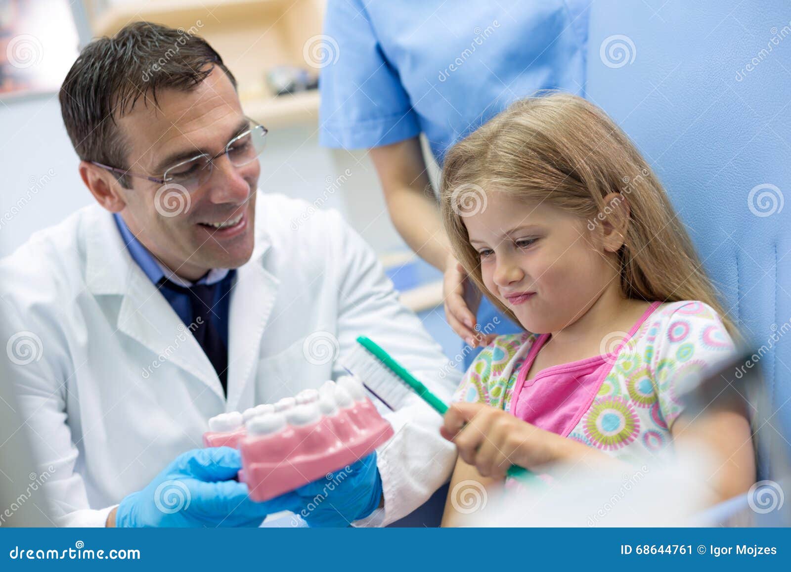 dentist teaches girl properly brushing on model of teeth