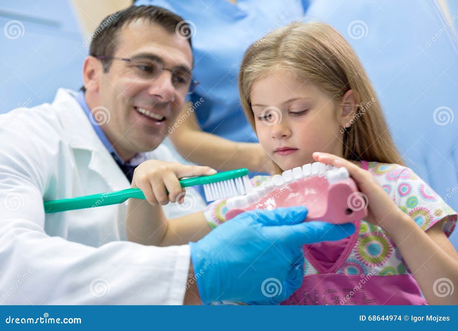 dentist teaching girl how to properly brush her teeth