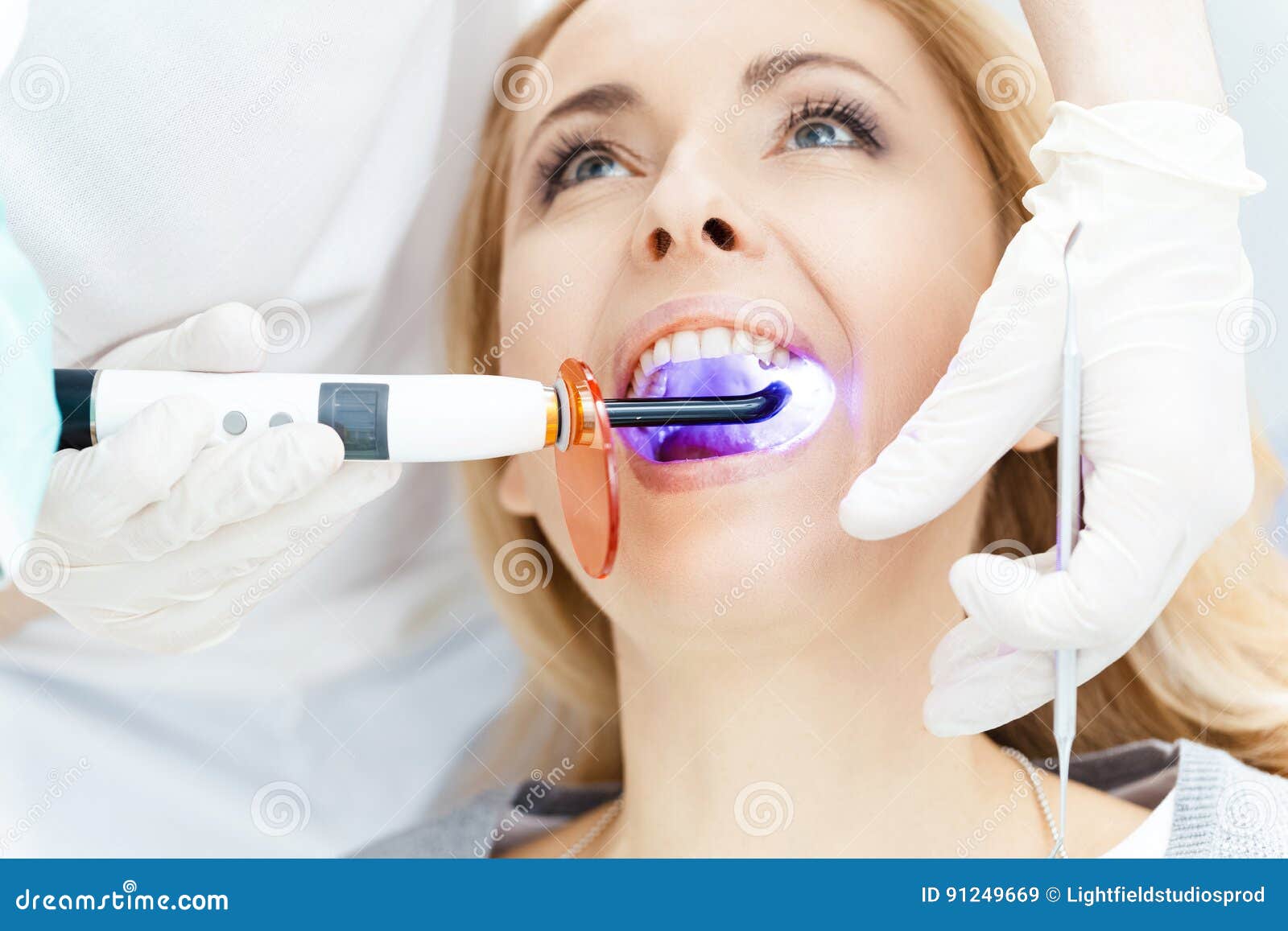 Dentist Using Dental Curing UV Lamp on Teeth of Patient Stock Image