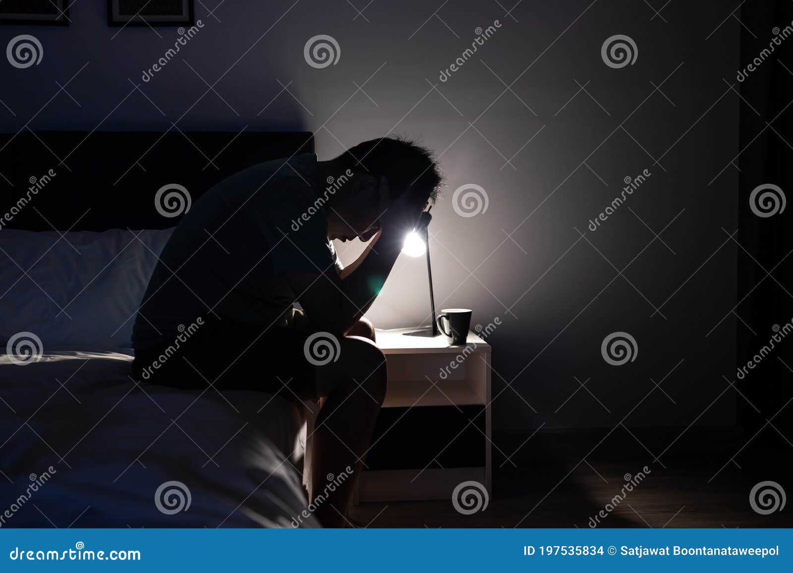 depressed asian man crying covering face with his hands,sitting on the bed at night,stressed worried people touching his head,