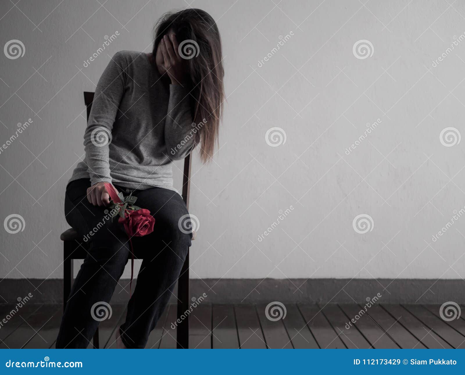 depressed broken hearted woman sitting and crying with red rose