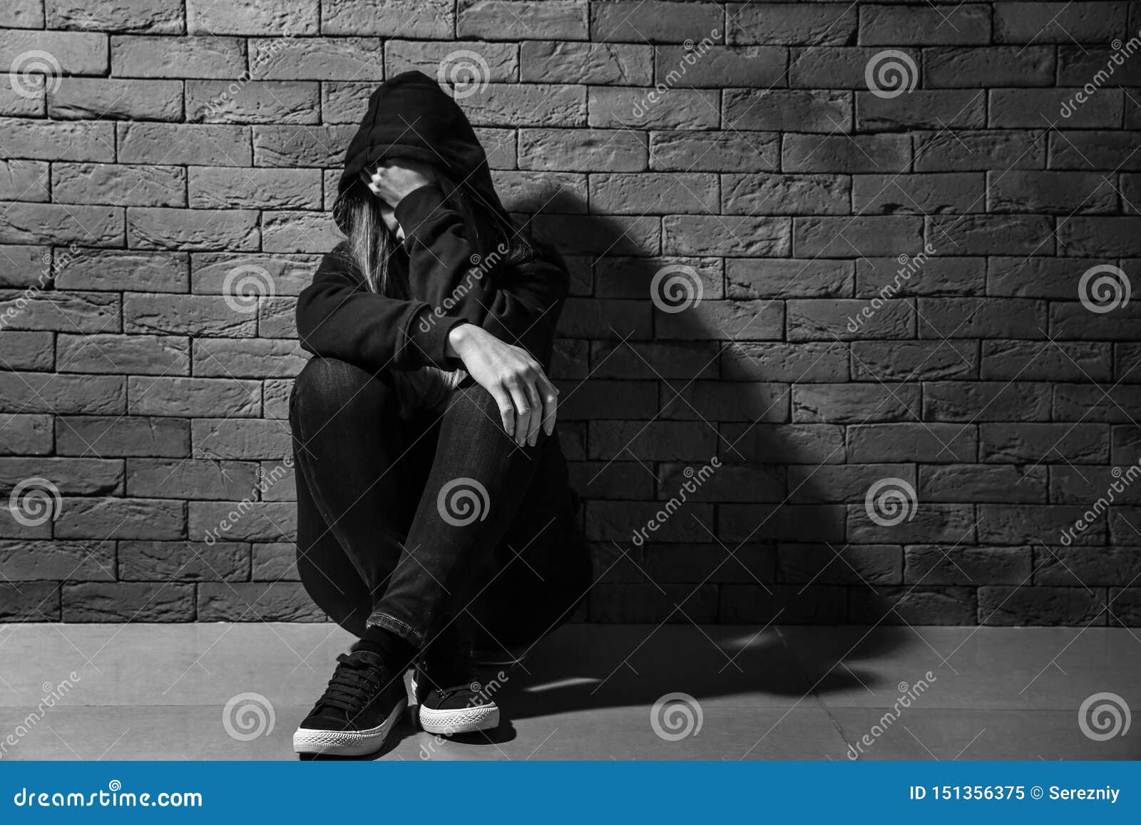 depressed female junkie near brick wall. concept of addiction