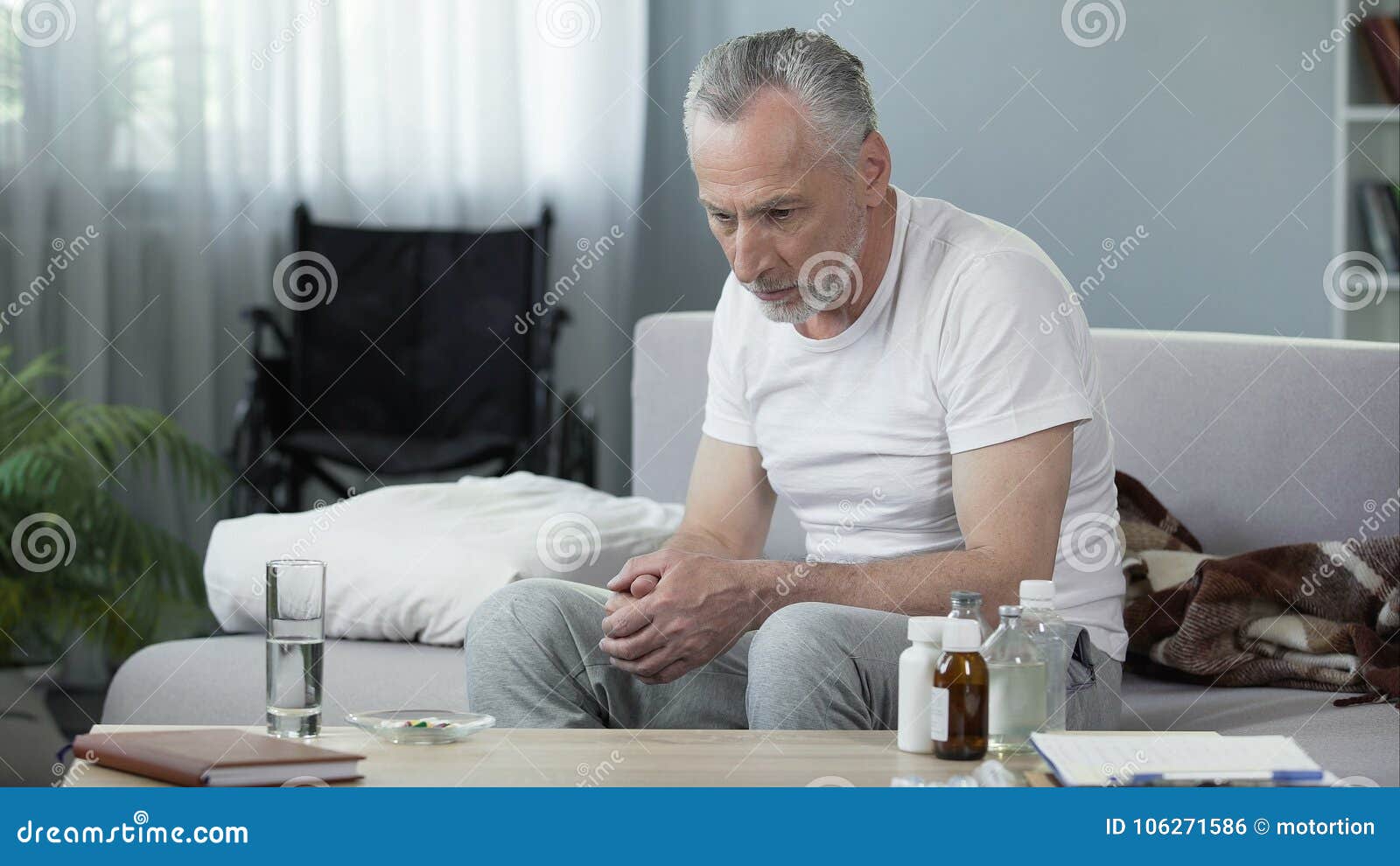 depressed senior male sitting on sofa at nursing home, loneliness and melancholy