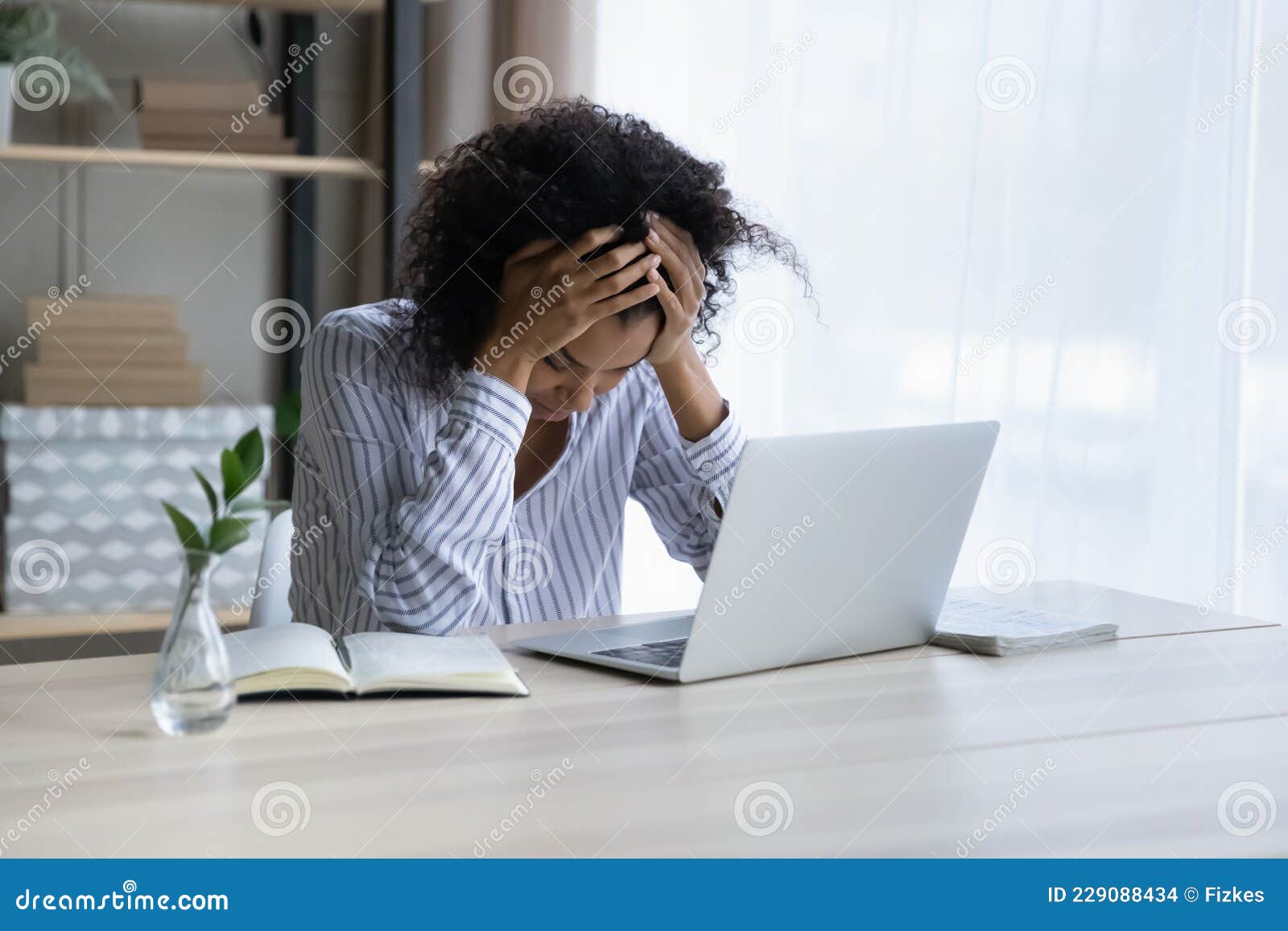 depressed upset black female sit at workplace hug head