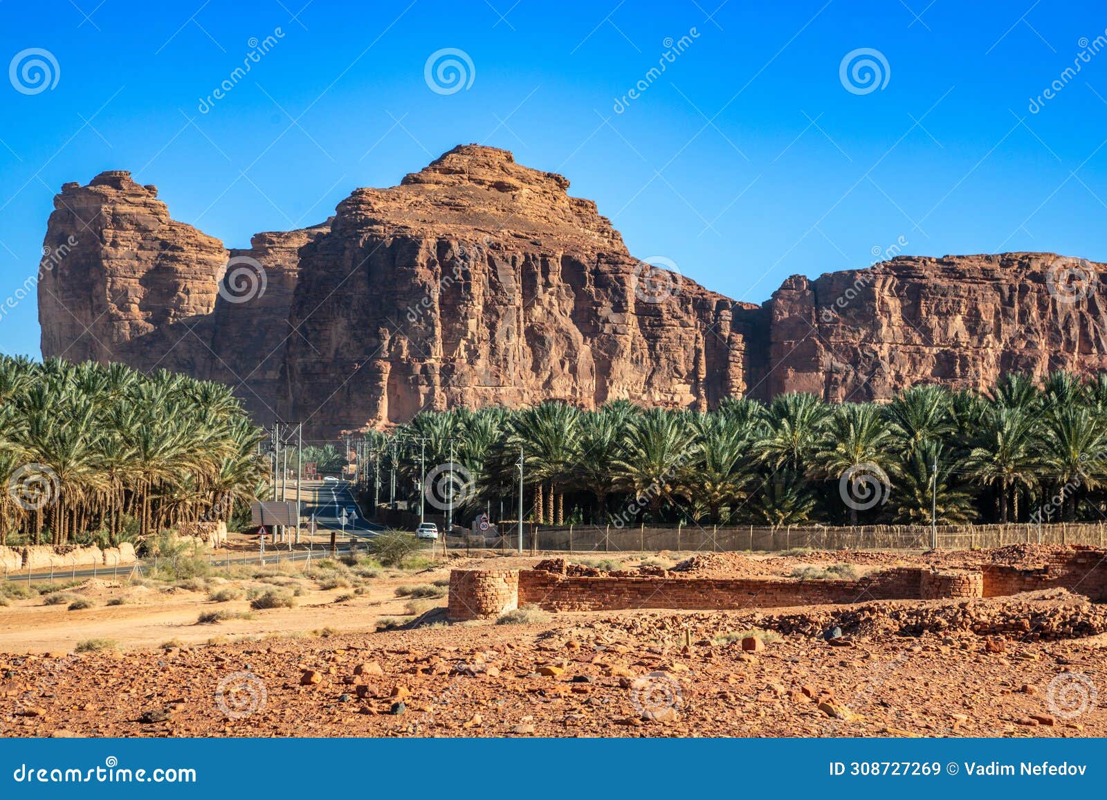 desert mountains with ruins of dadan and road with palms, al ula, madain salih, saudi arabia