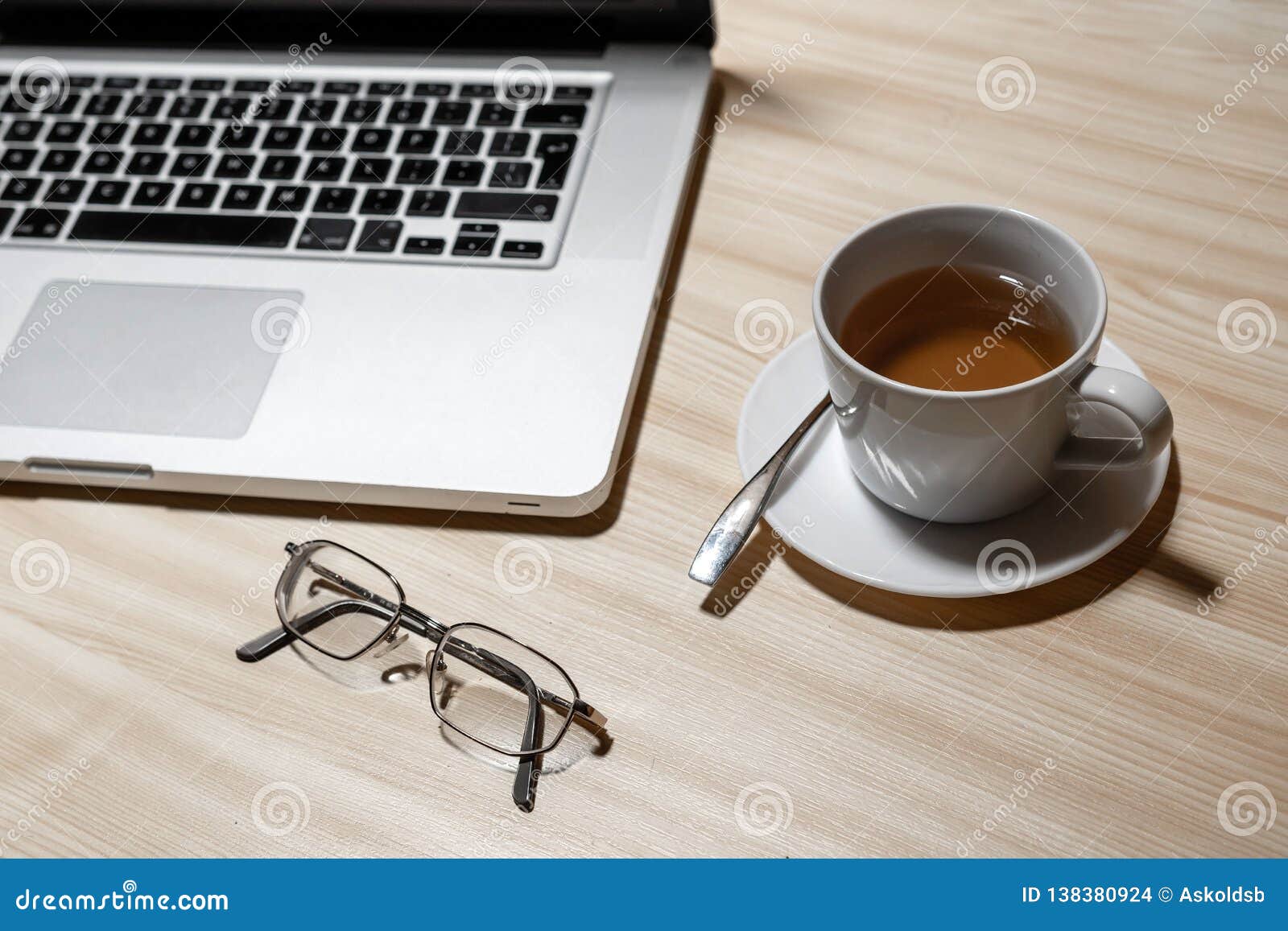 Desk with Laptop, Eyeglasses and a Cup of Tea on a Wooden Table Image
