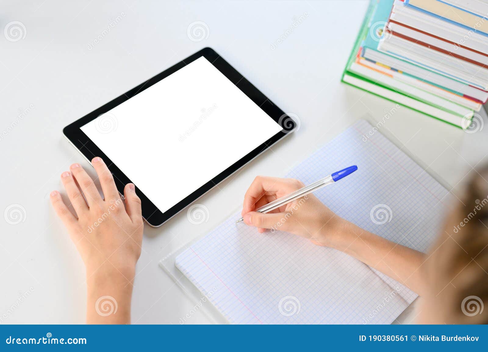 on the desk is a notebook, textbooks and a tablet with a blank display.