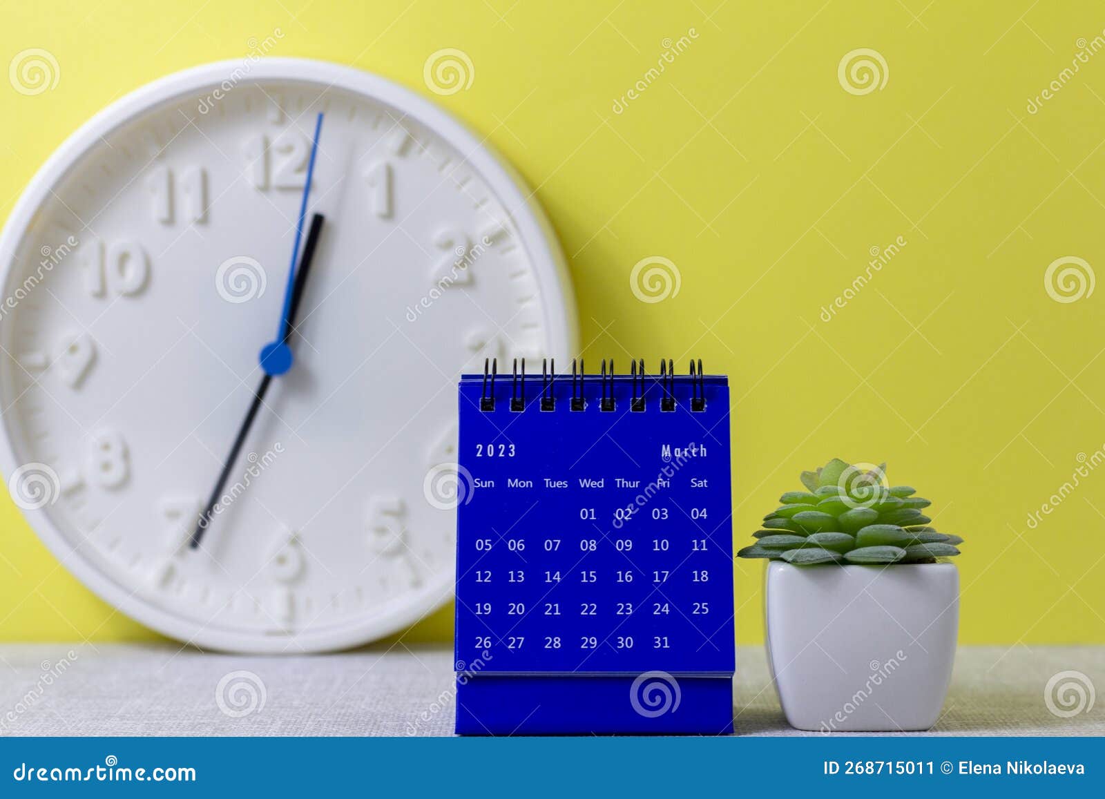 A Desktop Calendar for March 2023 and a Clock on the Table for Planning
