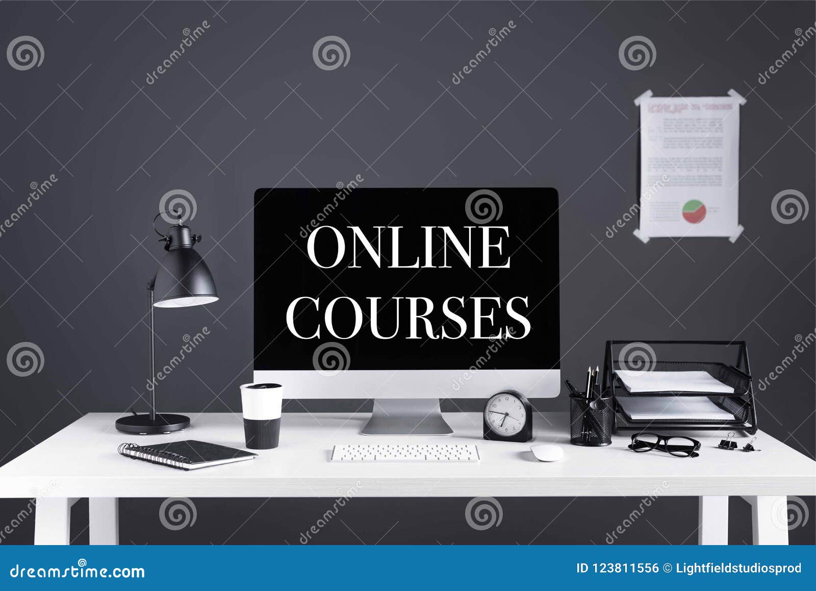 desktop computer with online courses inscription on screen, business chart, clock and office supplies