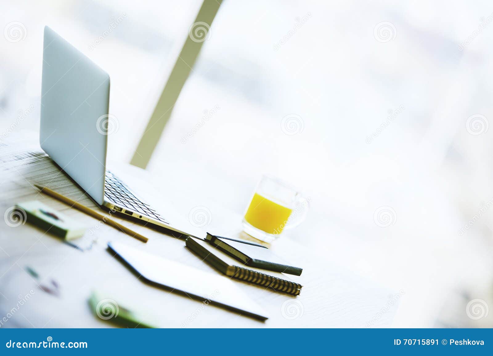 desktop notebook closeup desk orange juice smartphone various office tools blurry background 70715891