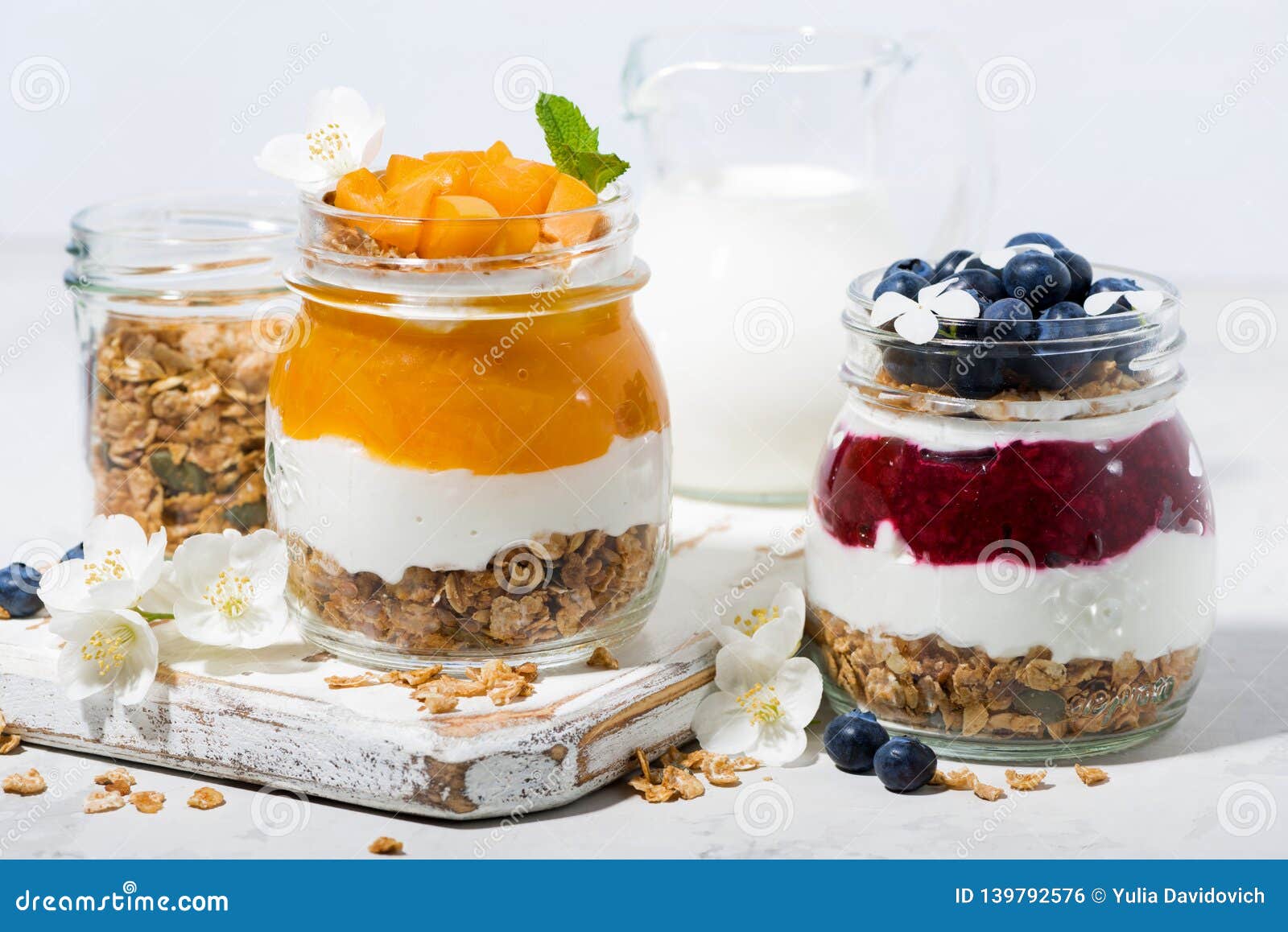 Desserts with Muesli, Berry and Fruit Puree in Jars on White Table