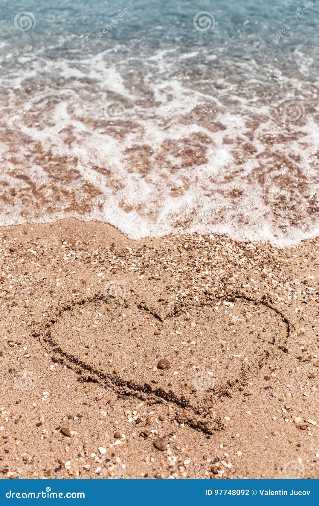 dessin d'une forme de coeur sur le sable et vague avec de la