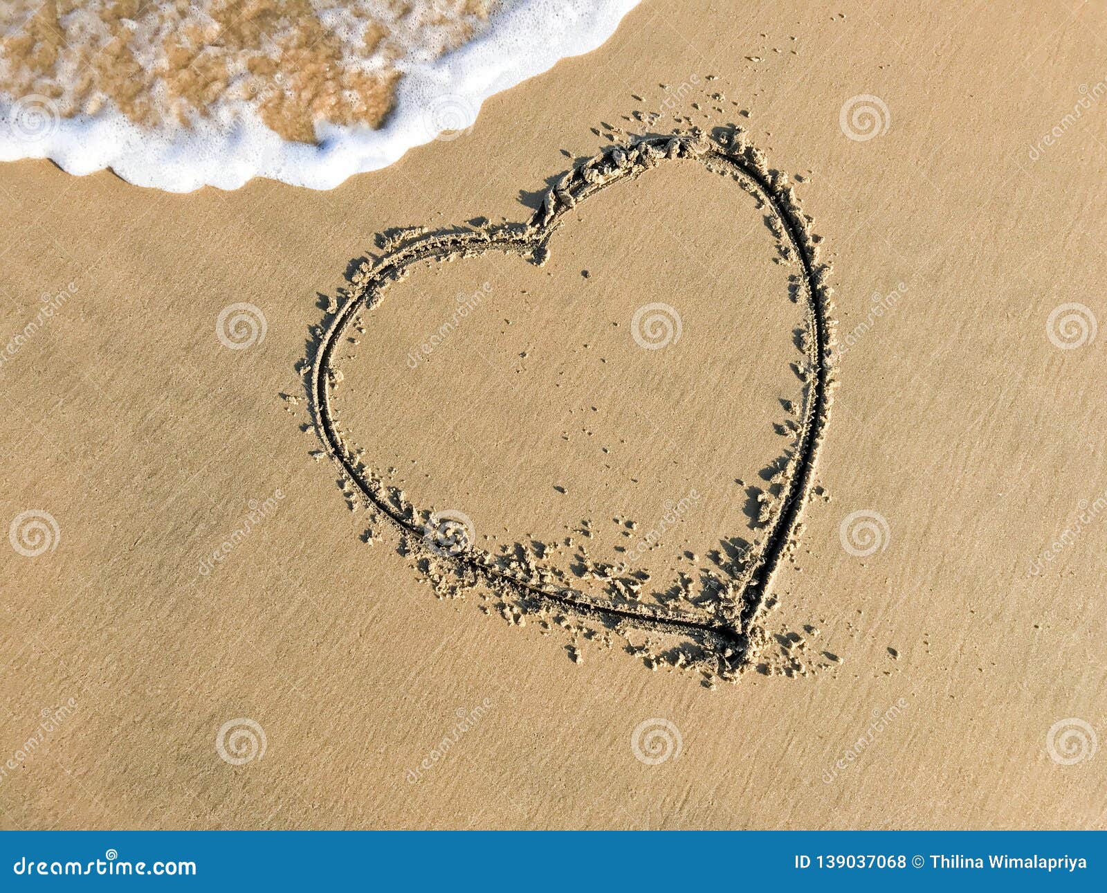 dessin d'une forme de coeur sur le sable et vague avec de la