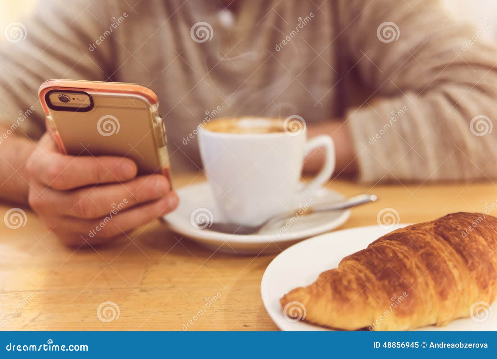 detail image of unrecognisable man drinking coffee and holding smart phone while having breakfast in restaurant.