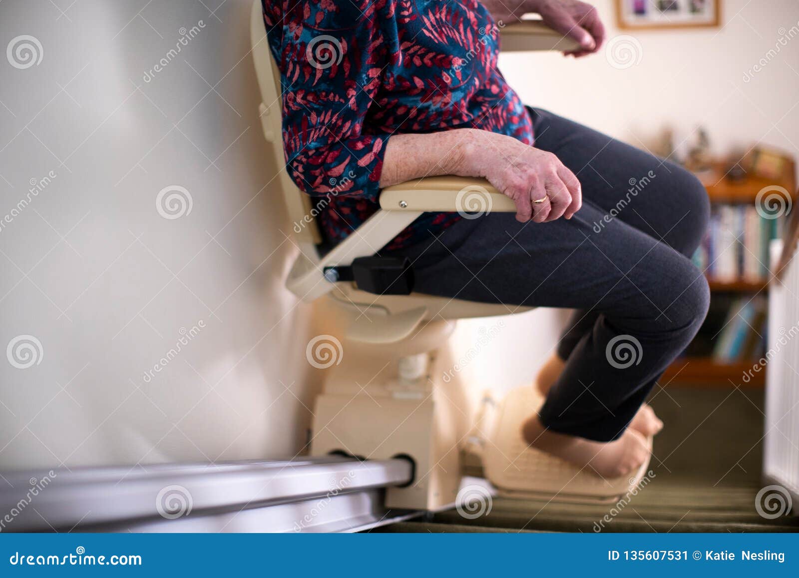 detail of senior woman sitting on stair lift at home to help mobility