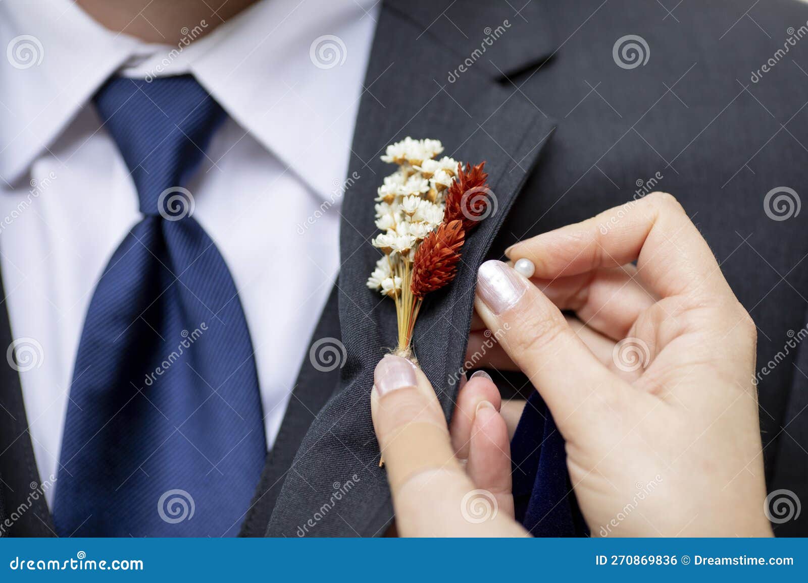 detail shot of hands pinning on a boutonnniere on a grooms suit