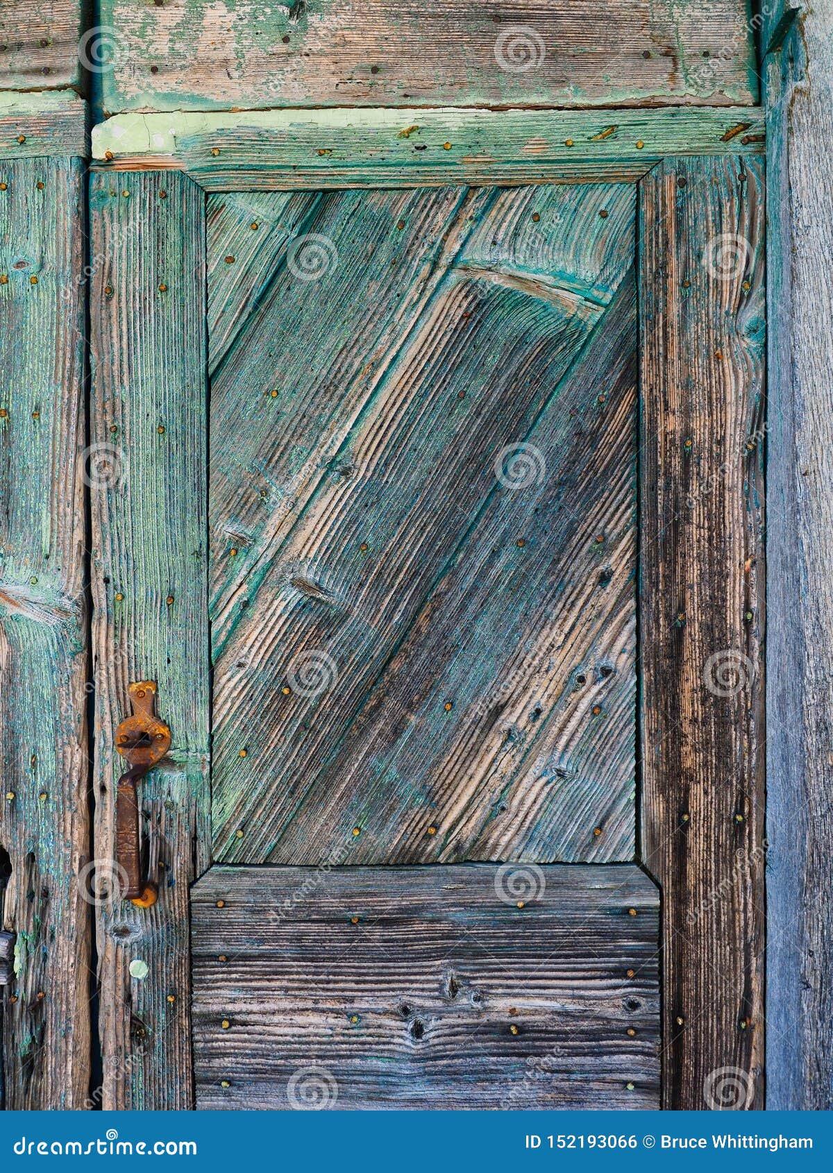 Detalj av den texturerade gamla blått målade trädörren. Detalj av en gammal träingångsdörr, med texturerad urblekt och flagnande blå målarfärg En metafor för torr åldrig flagnande hud, med det crudely bultade dörrhandtaget