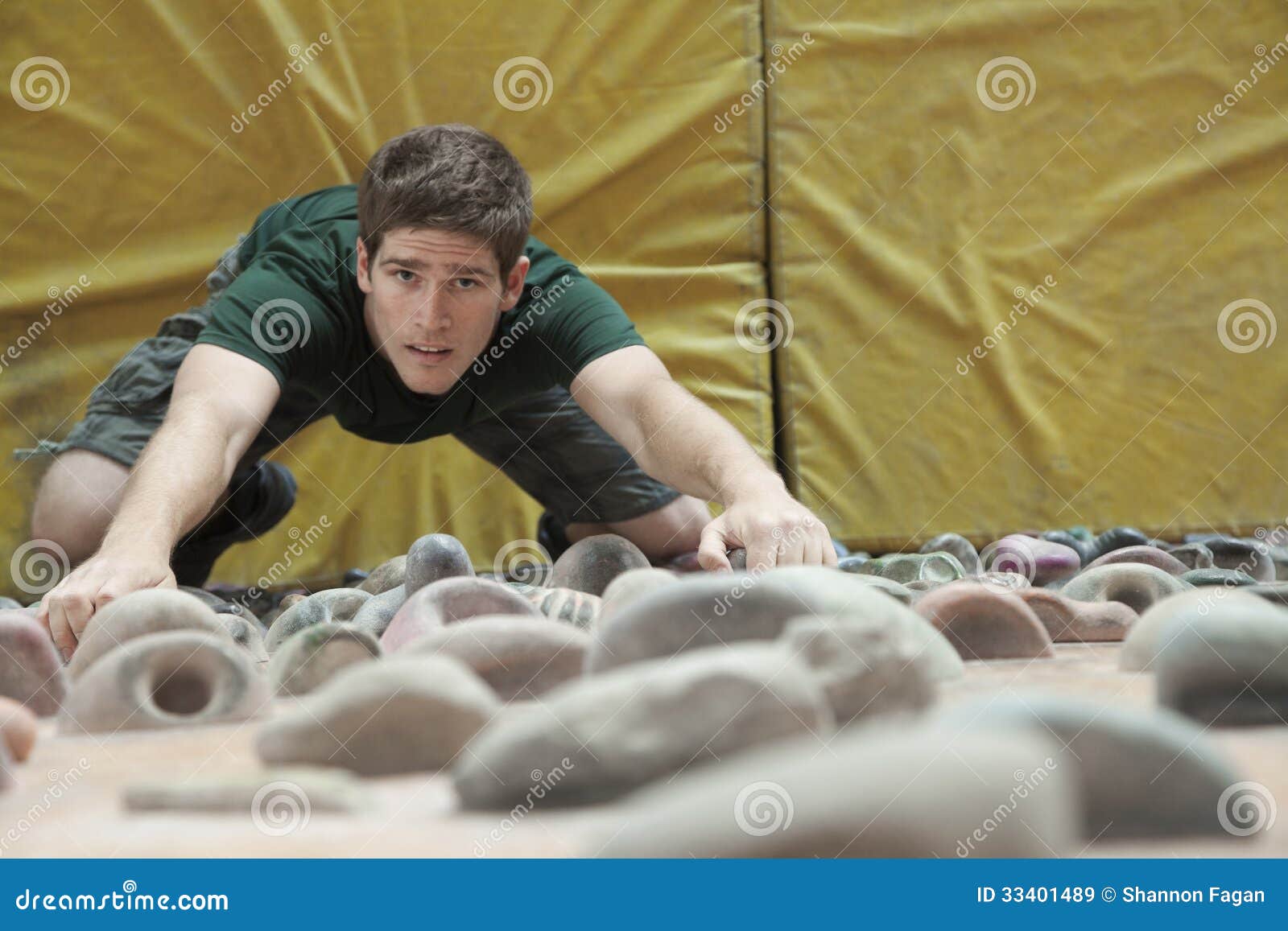 determined young man climbing up a climbing wall in an indoor climbing gym, directly above