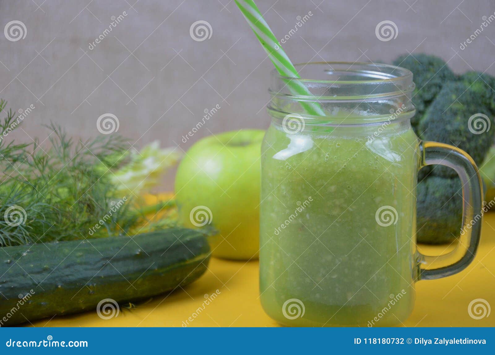 Detox gezonde groene smoothie in metselaarkruik met ingrediënten: spinazie, selderie, komkommer, sla, gember, venkel, kalk en broccoli op een dienblad op gele achtergrond Schoon het Eten Concept Hoogste mening