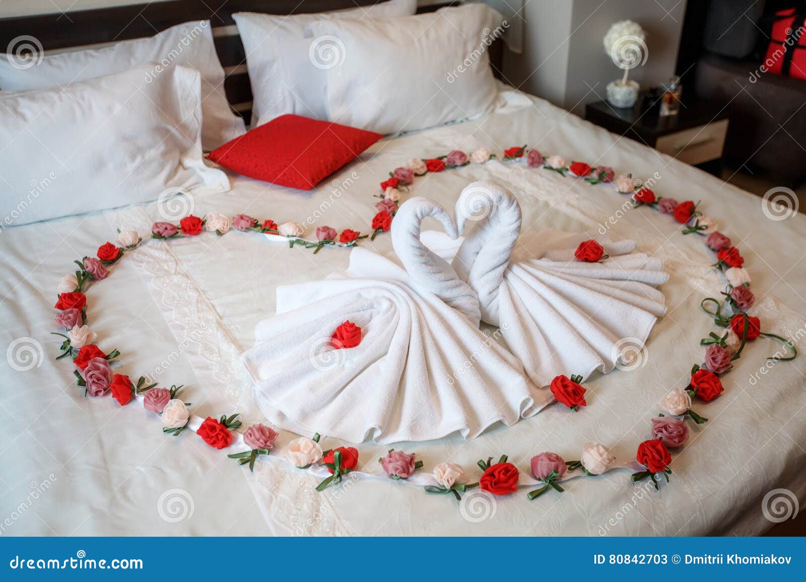 photo stock deux cygnes faits de serviettes formant la forme de coeur sur le lit image