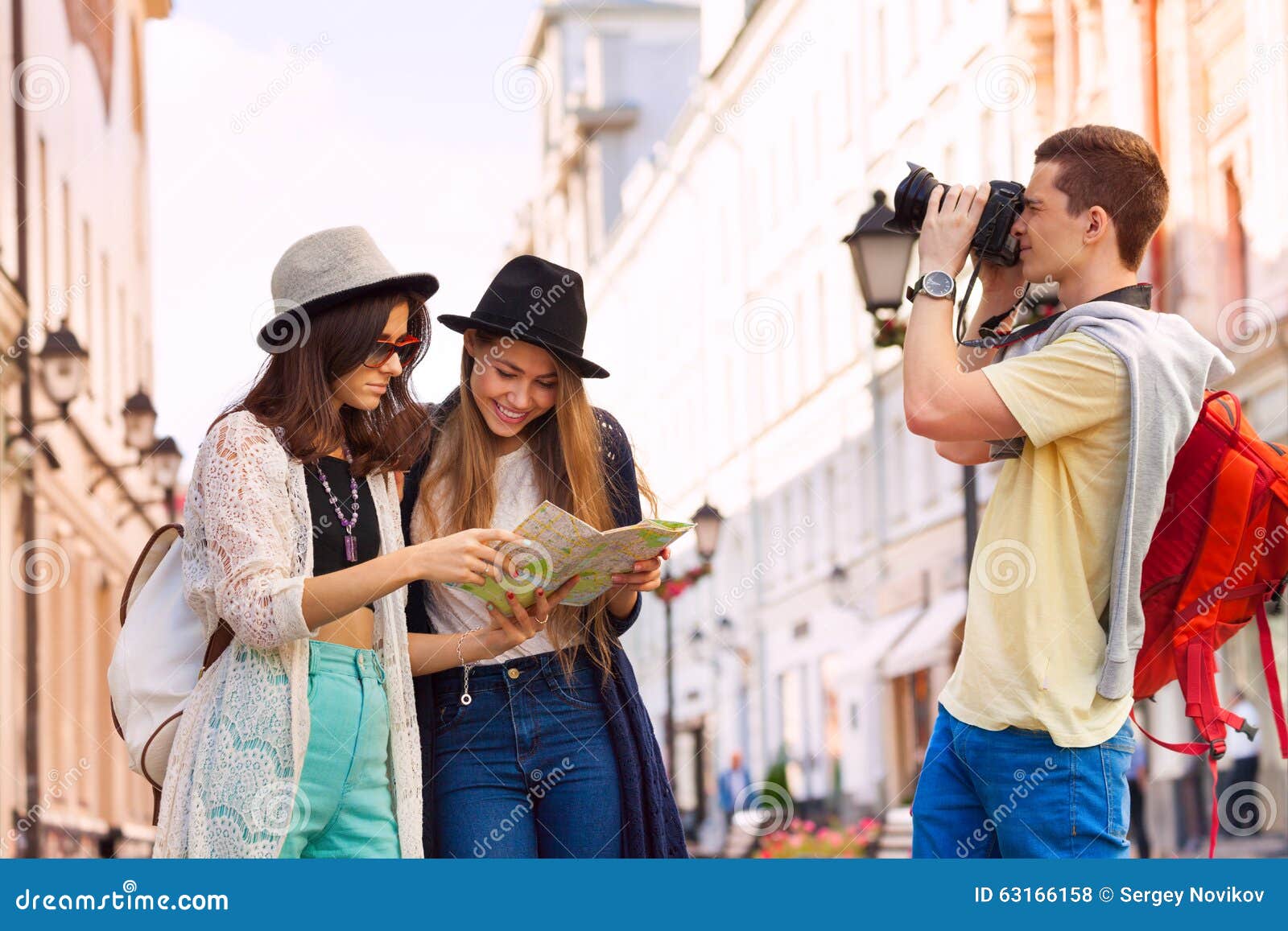 Deux jeunes femmes tiennent la carte et le type de ville avec l'appareil-photo. Deux jeunes femmes avec la carte de ville et type avec le tir d'appareil-photo comme touristes sur la rue européenne pendant le temps de jour d'été