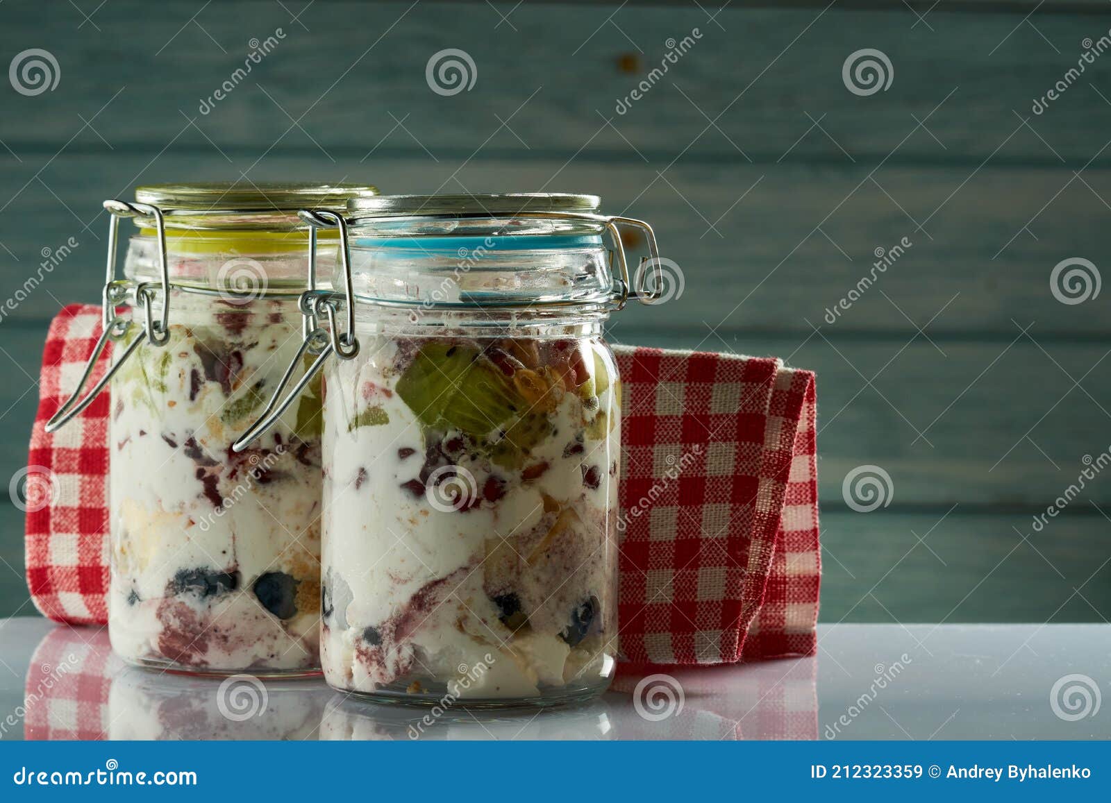 Un Pot En Verre De Yaourt Avec Des Fruits Sur Une Planche De Bois