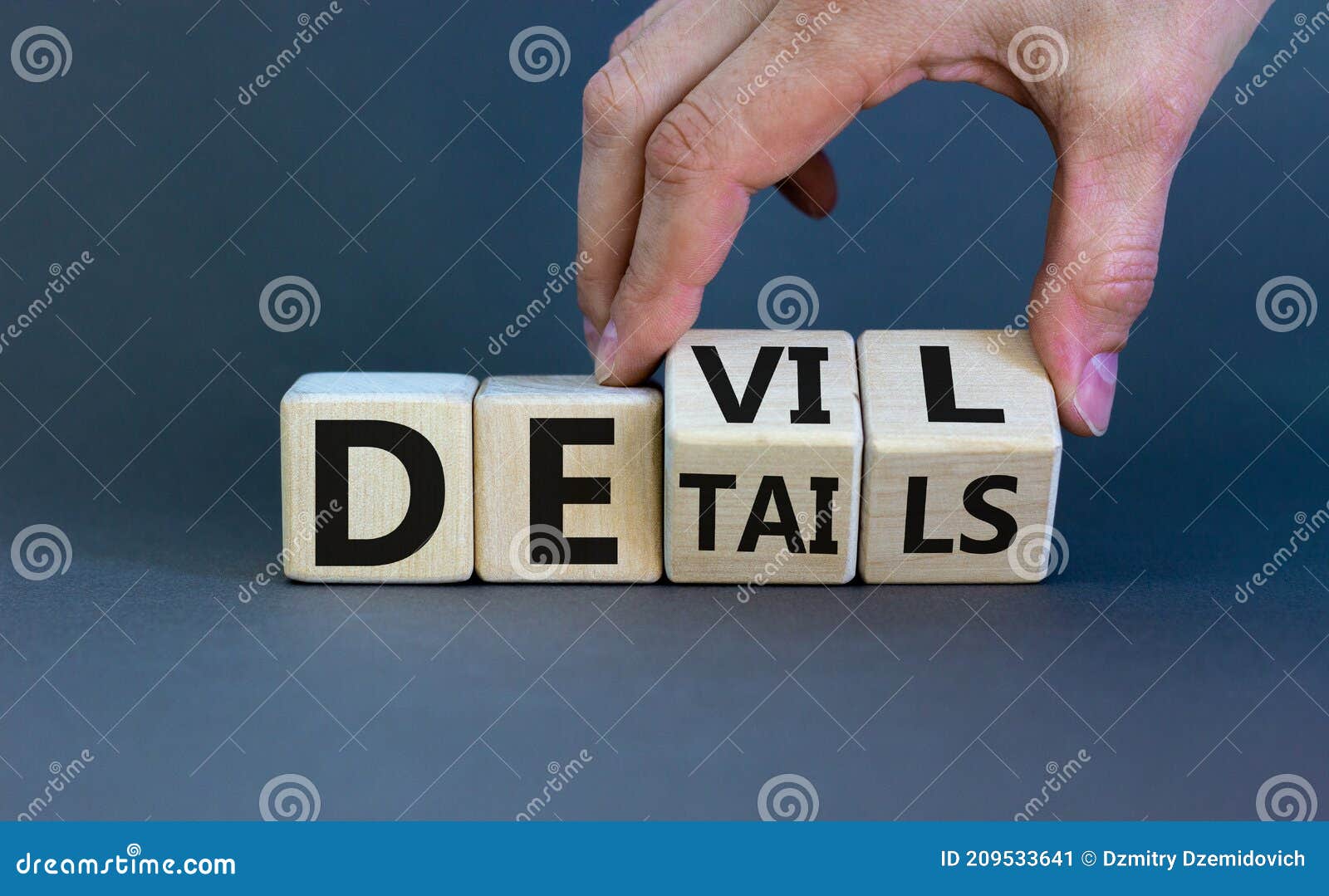 devil in the details . businessman hand turns cubes and changes the word `details` to `devil`. beautiful grey background