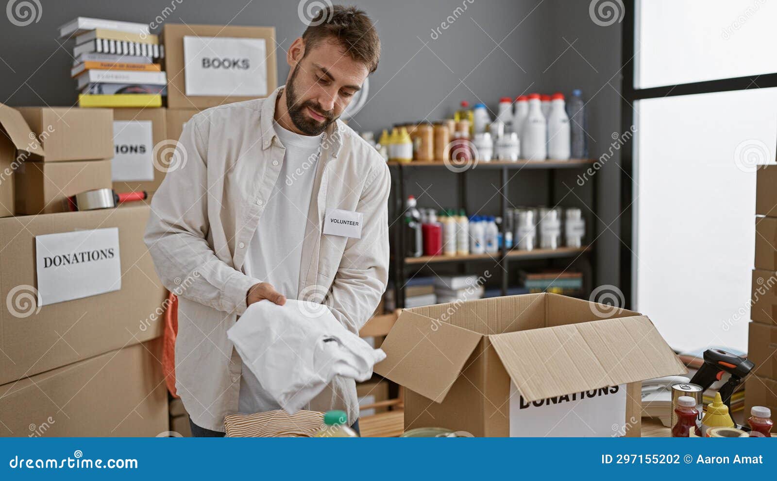 devoted young hispanic man working tirelessly, putting clothes in cardboard box at charity center, embodying community spirit and
