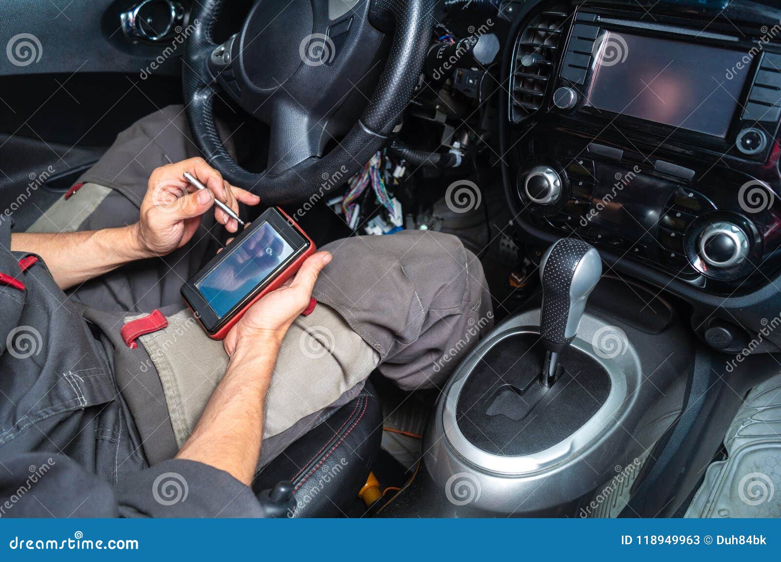 diagnostics of car failures: an electrician in gray clothes is sitting in the car`s interior and reading the trouble