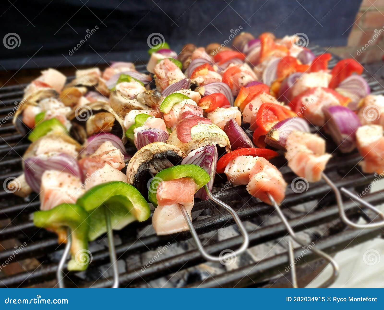 diced outdoor pork belly skewers withb vegetables like purple onion, red and green pepper on a charcoal barbecue in london uk