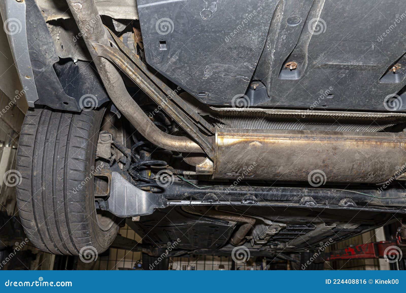 Die Auspuffanlage im Auto von unten gesehen, sichtbare Endschalldämpfer und  Rad, das Auto ist auf dem Lift in der Autowerkstatt Stockfotografie - Alamy