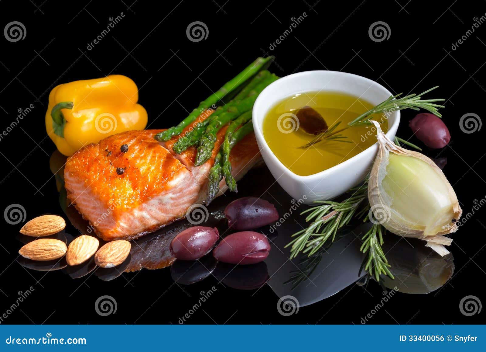 Dieta mediterránea omega-3. Filete de pescados, aceitunas, nueces e hierbas en fondo negro con la reflexión.
