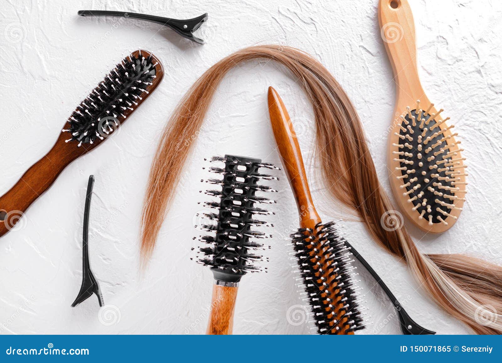 Different Brushes and Strand of Hair on White Textured Background Stock