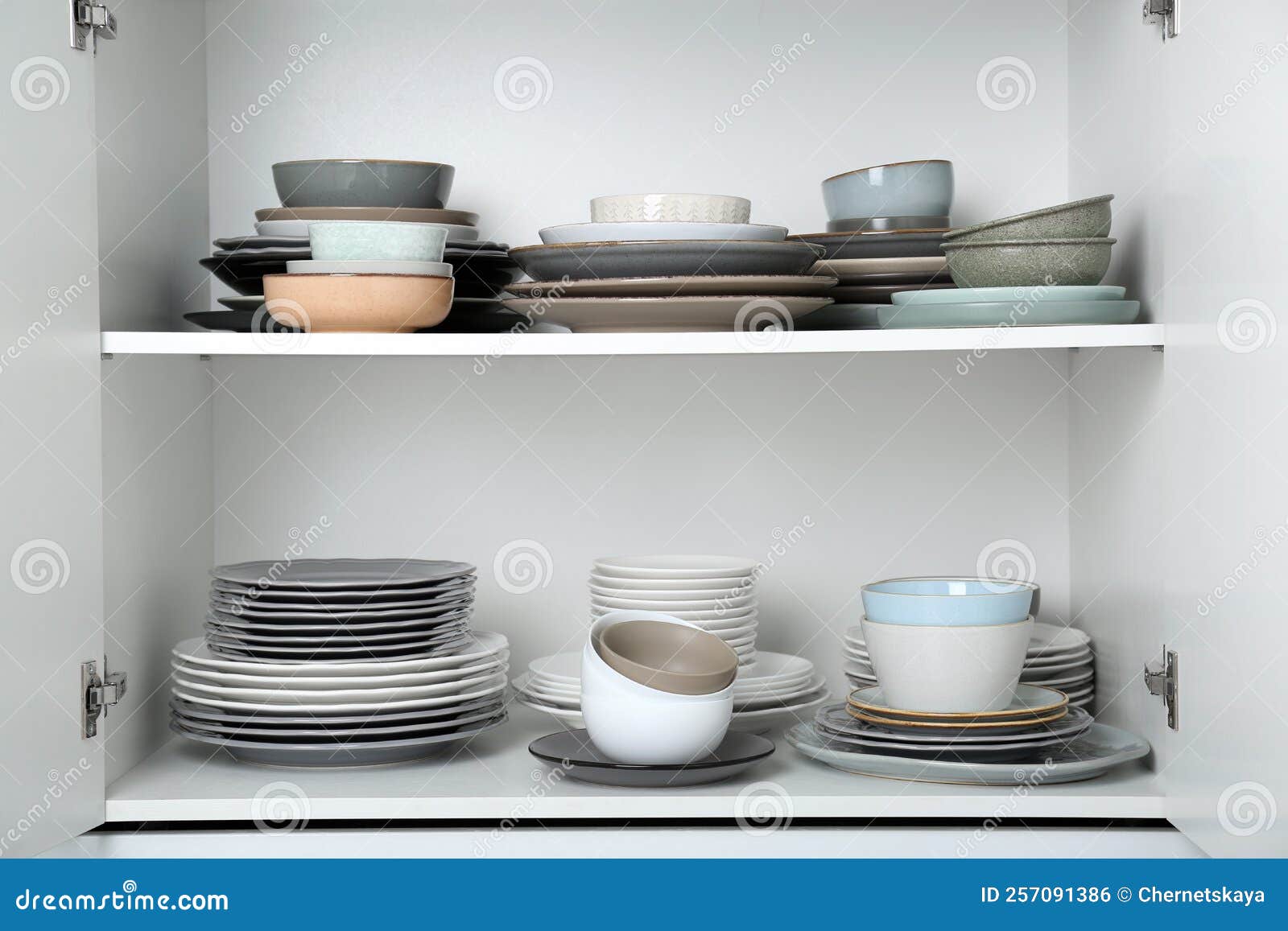 Different Clean Plates and Bowls on Shelves in Stock Photo