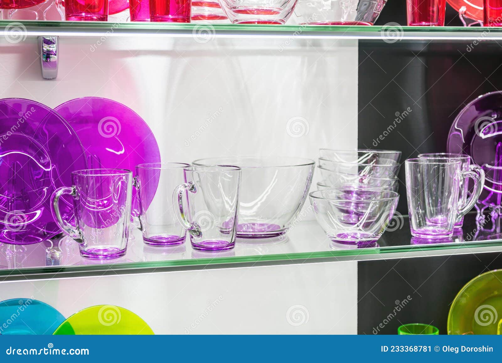 Differentcolored Glass Cups, Plates and Saucers are on the Counter