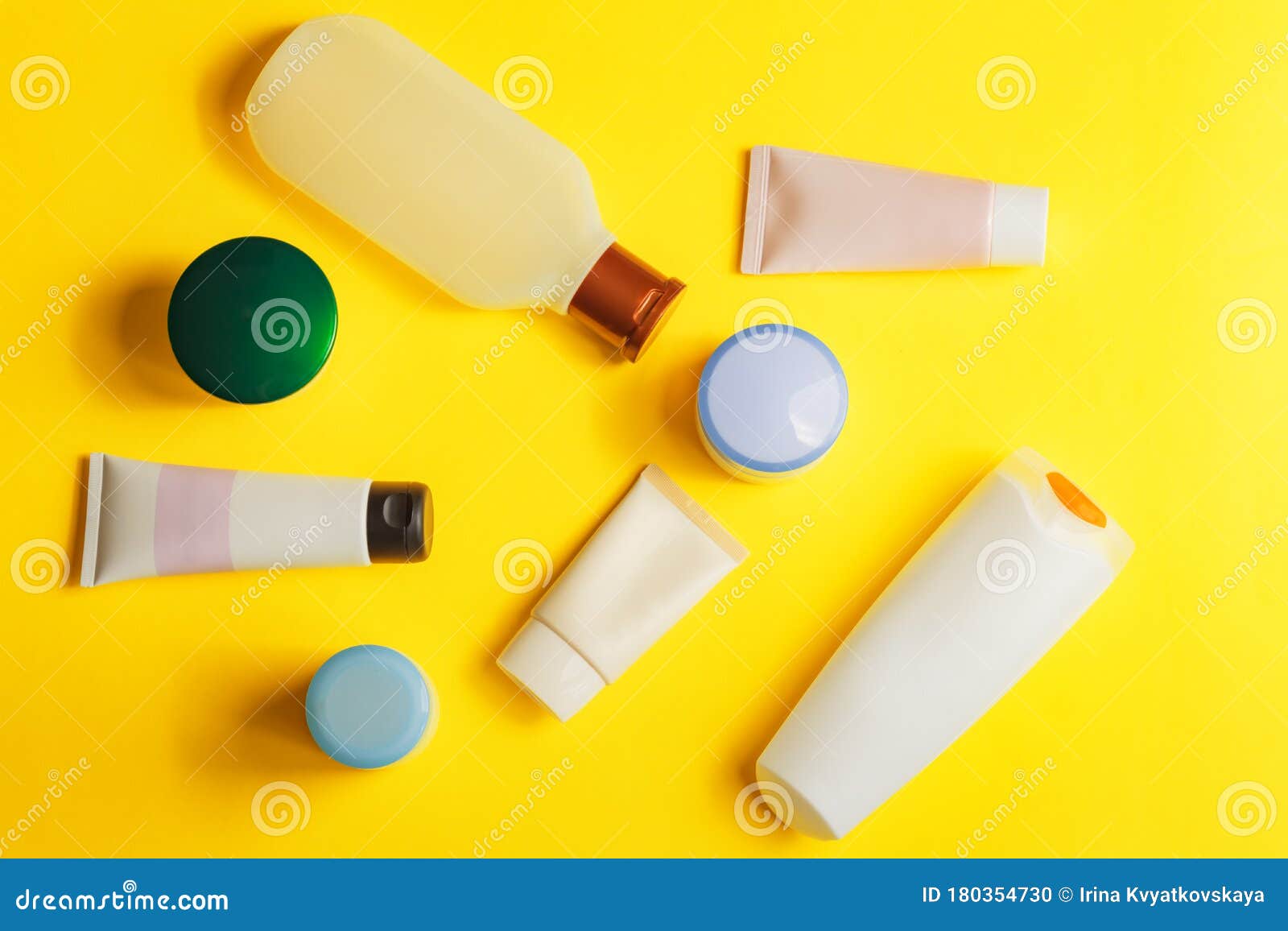 different colorful beauty toiletries on yellow background. men and women care products for hair and body. top view