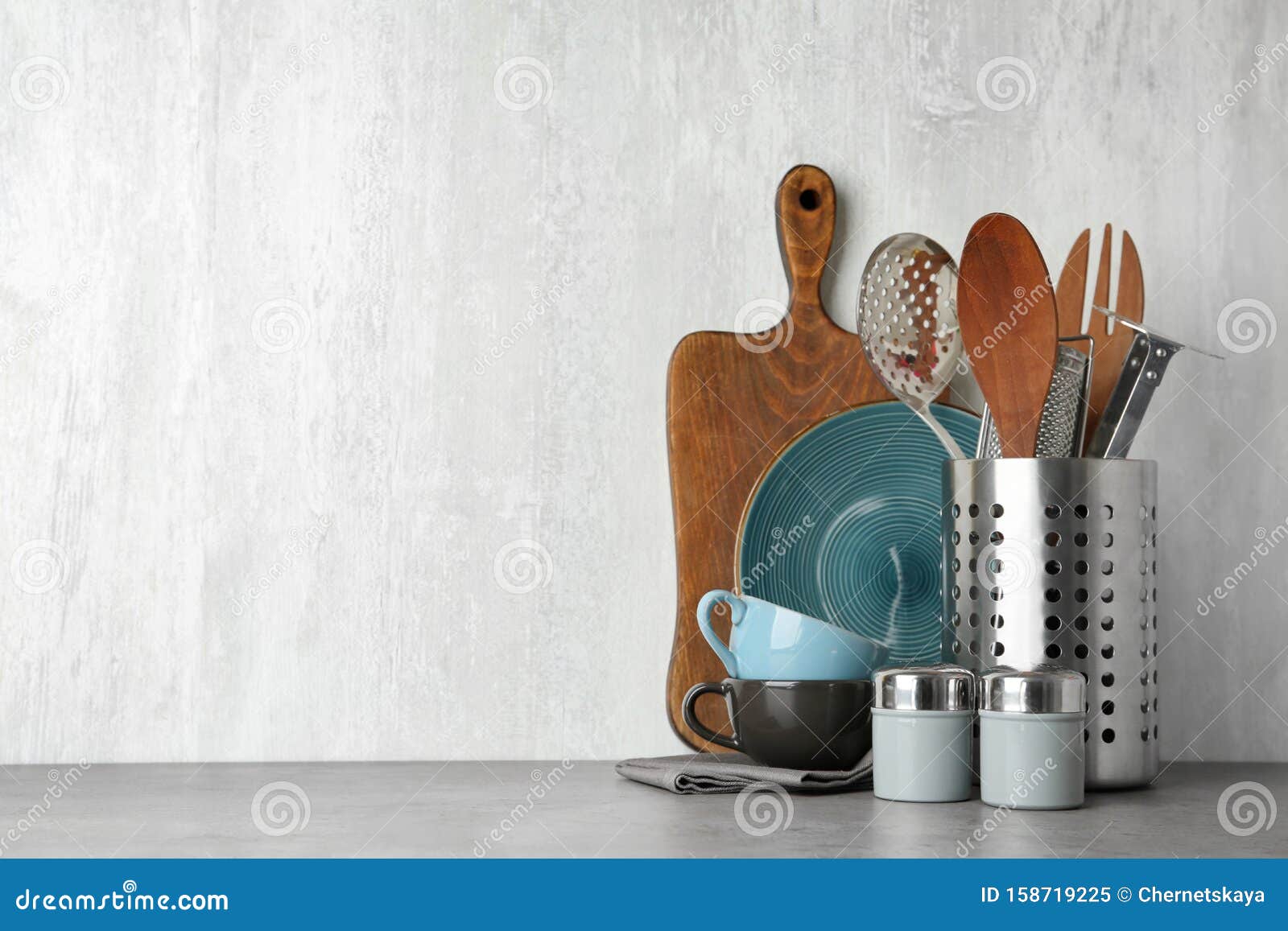 Different Kitchen Utensils on Grey Table Against Light Background