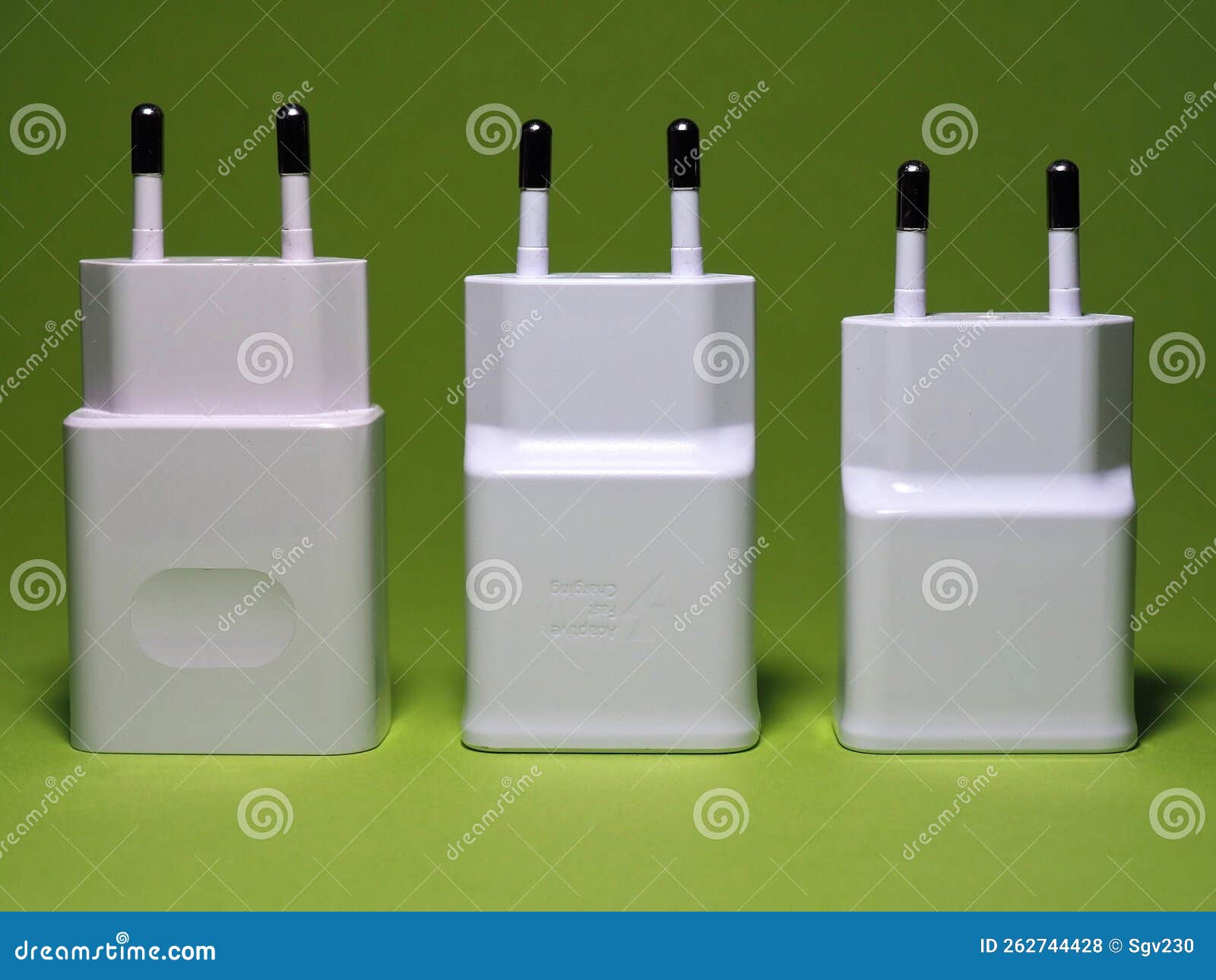 Different Size and Power Chargers on a Green Background Stock Photo