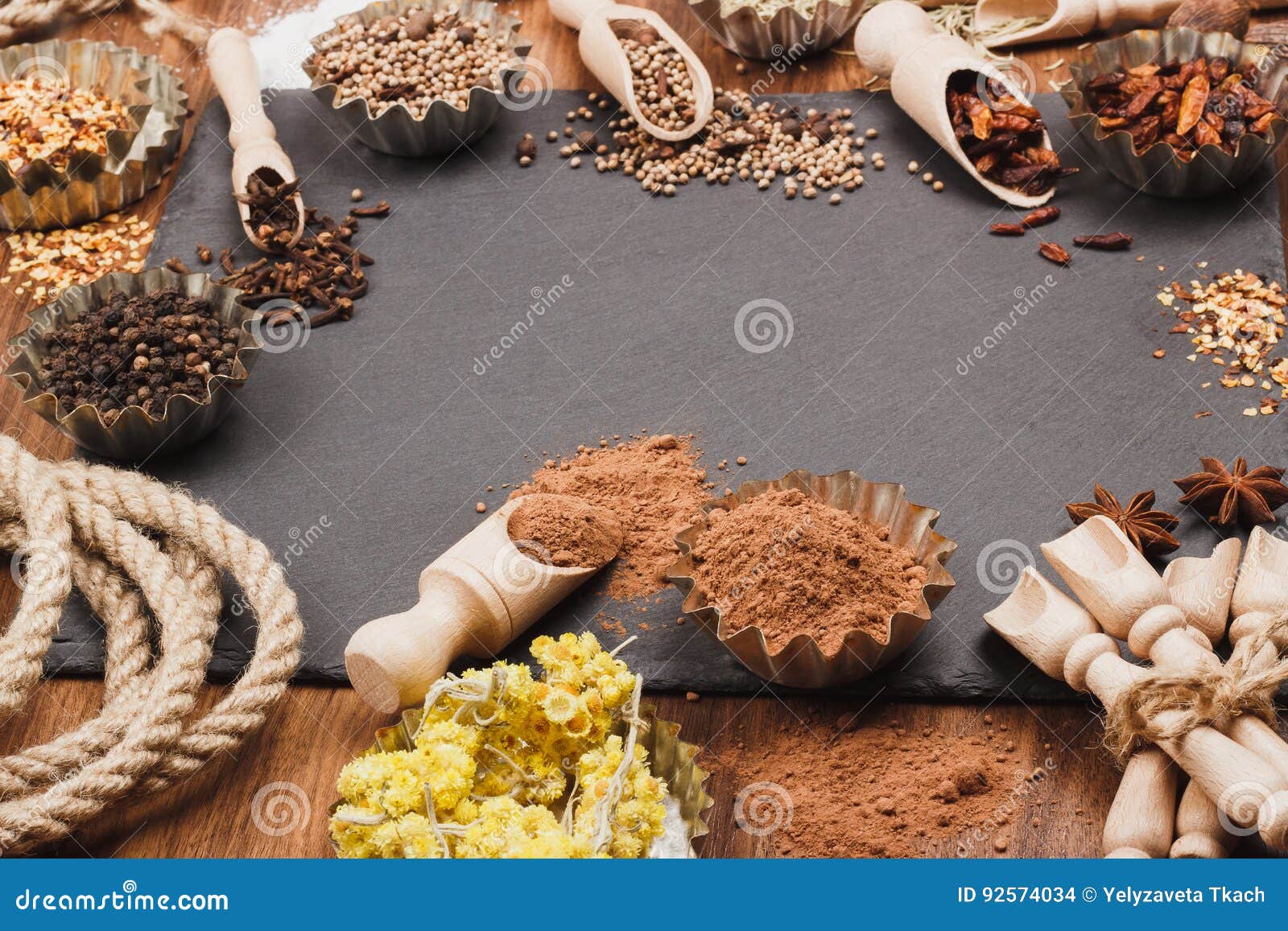 different spices in bakeware with wooden scoops on the slate slone