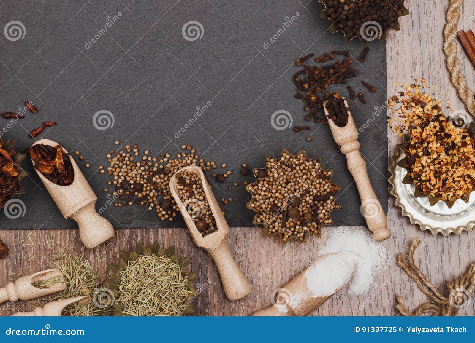 different spices in bakeware with wooden scoops on the slate slone background
