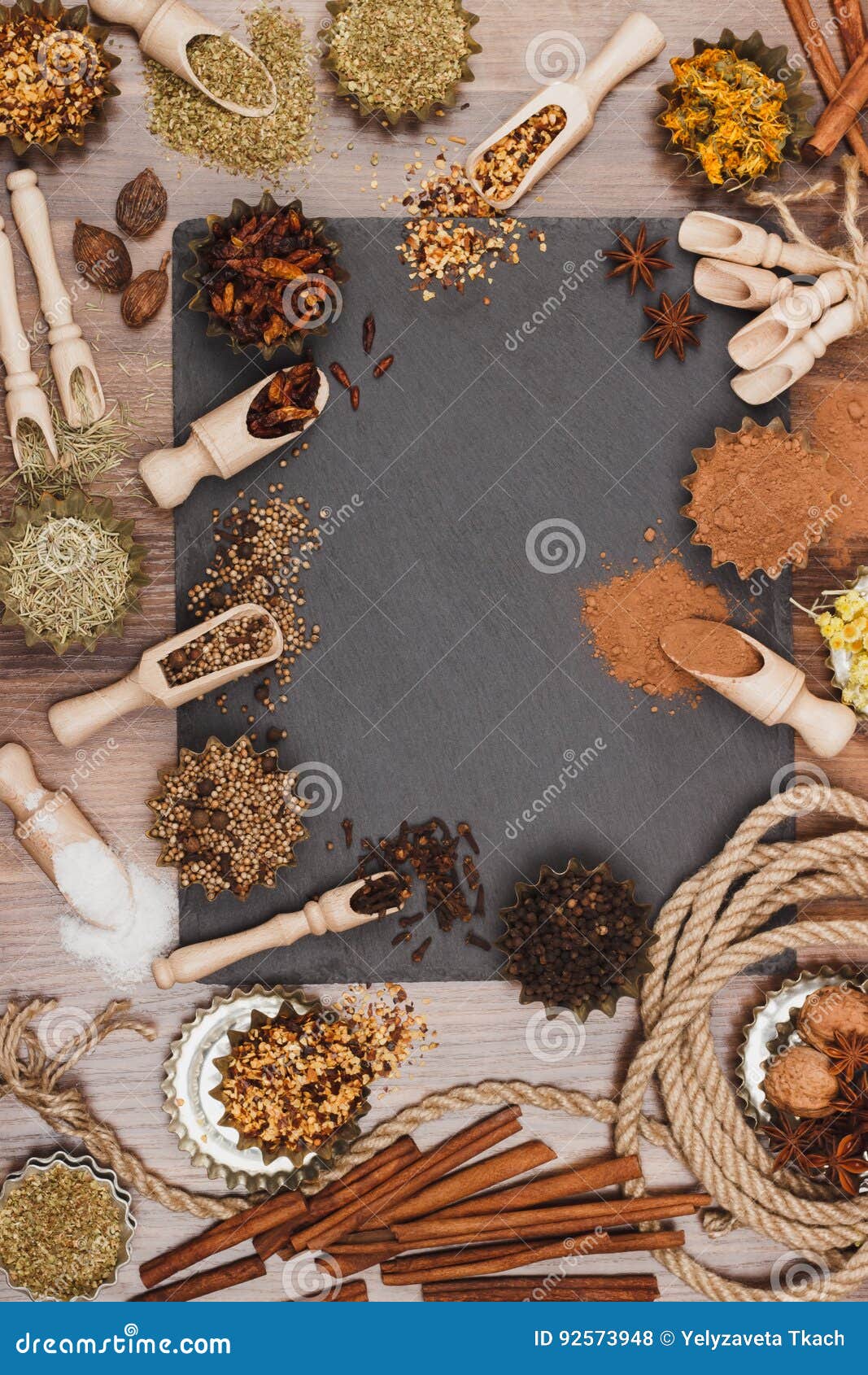 different spices in bakeware with wooden scoops on the slate slone