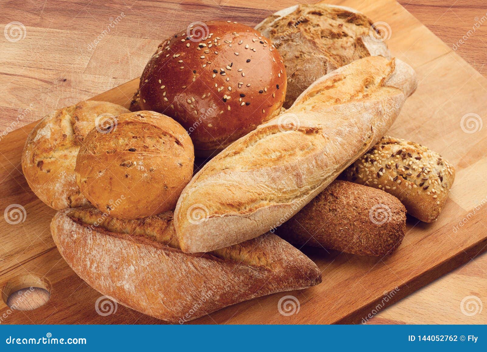 Different Types of Bread on Wooden Kitchen Cutting Board Stock Photo
