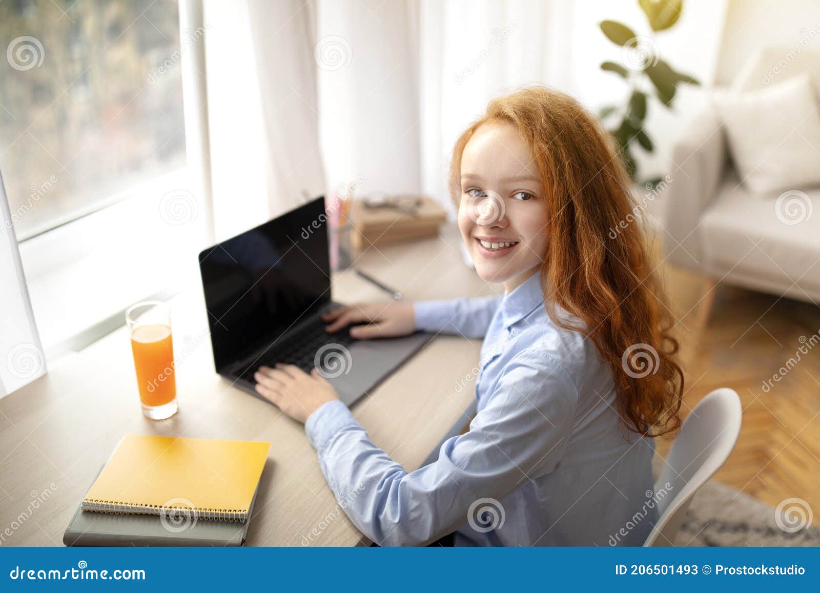 girl using laptop for elearning, looking back at camera