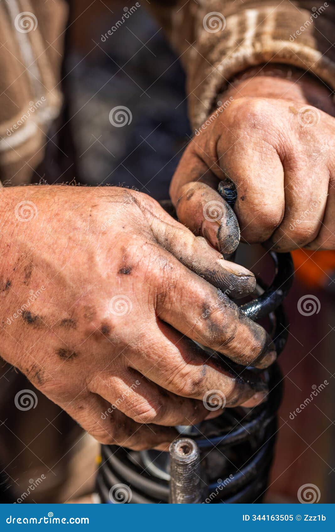 the calloused hands of a mechanic assembling compressed coil spring during diy car repairs.