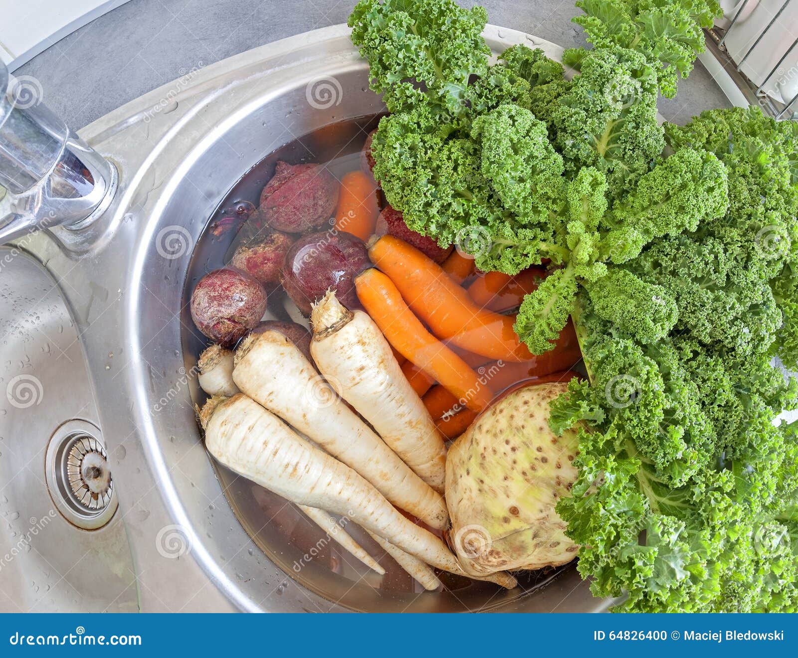 Dirty Vegetables in a Kitchen Sink Filled with Water Stock Photo