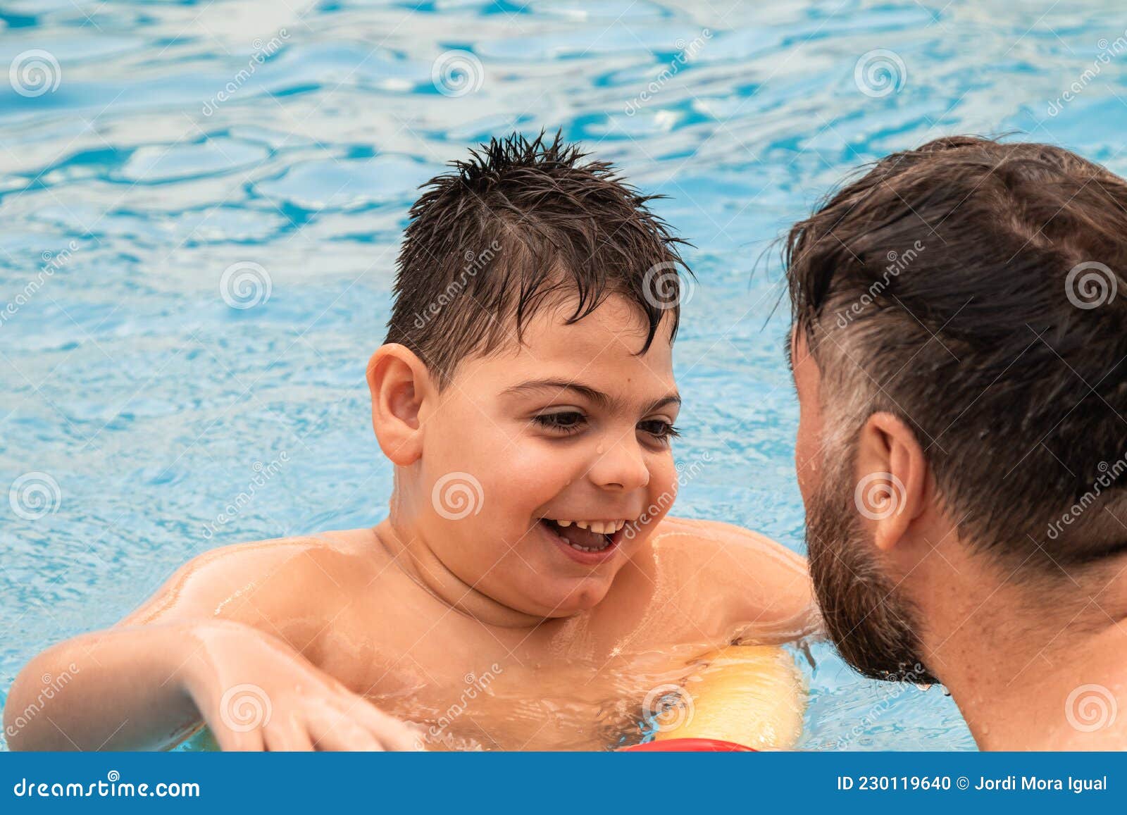 Disabled Boy with a Float Laughs As he Plays and Swims in a Pool with