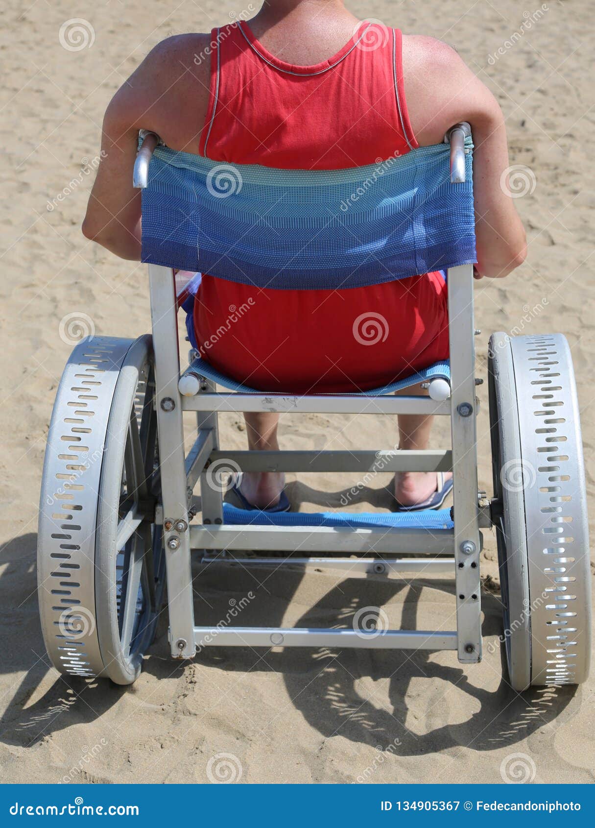 disabled man with undershirt on the wheelchair in the sandy beac