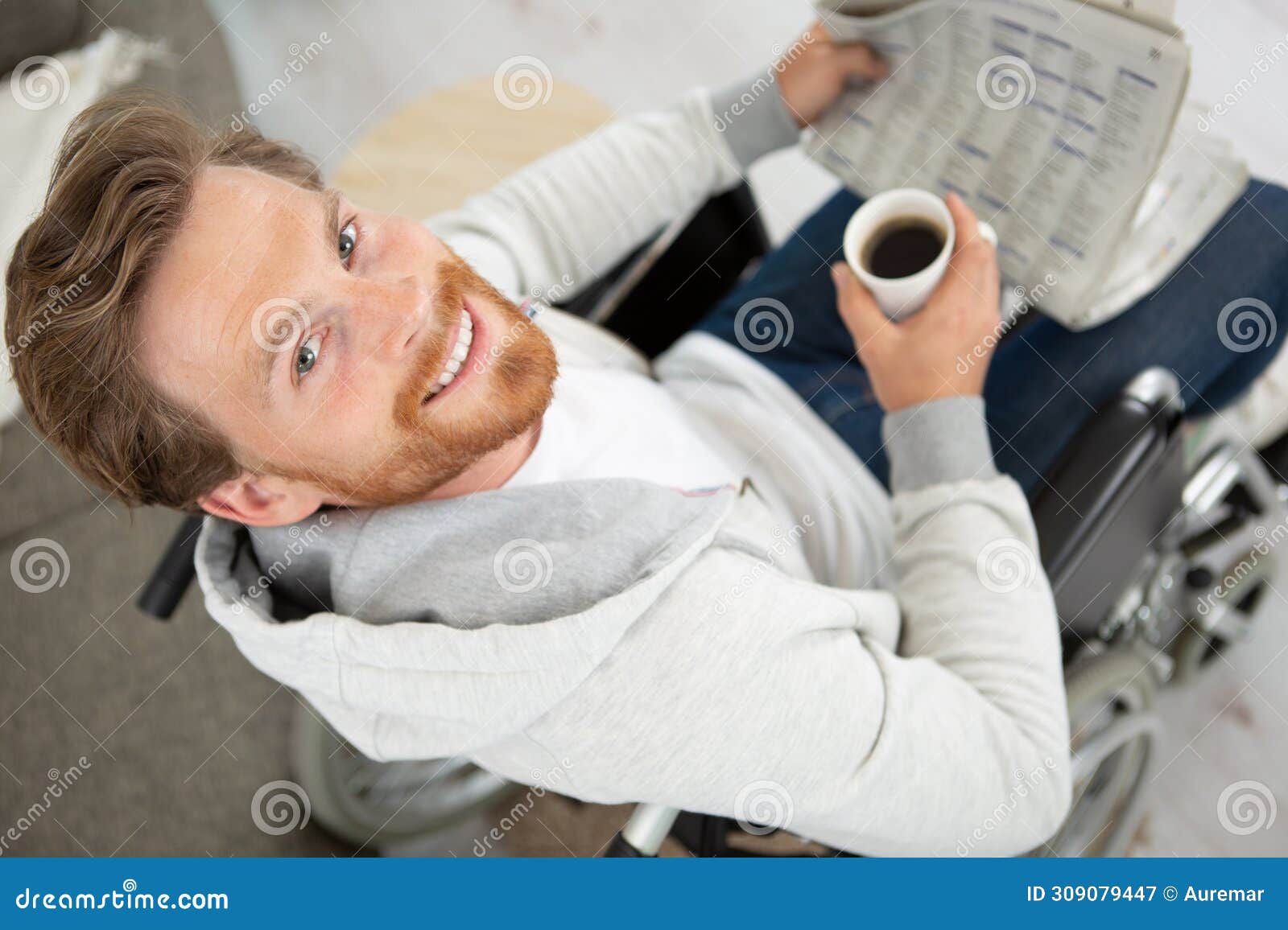 disabled man in wheelchair holding coffee and newspaper