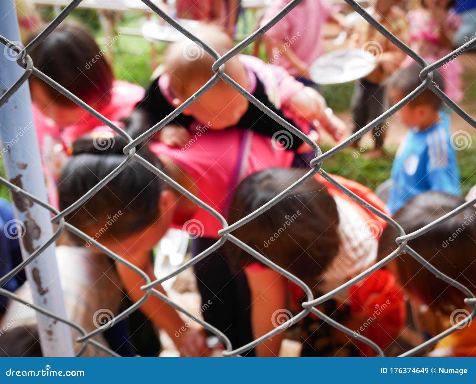 disadvantaged woman and kids behind the fence stock photo
