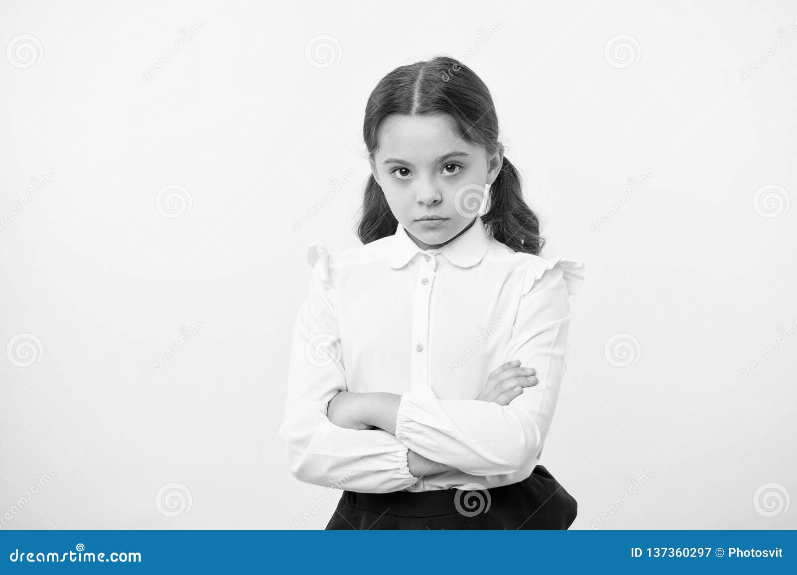 disagreement and stubbornness. girl school uniform serious face offended yellow background. kid unhappy looks strictly